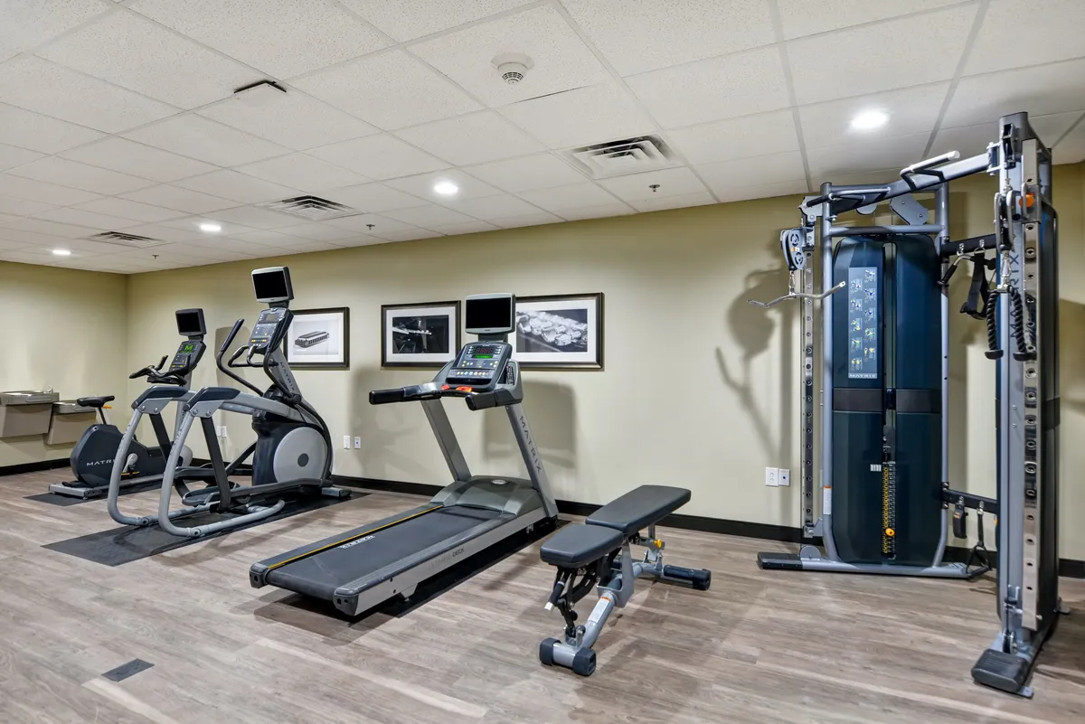 A fully equipped fitness center with treadmills, elliptical machines, a weight bench, and a multi-gym machine. The room is spacious, clean, and set up for a variety of workouts, appealing to guests who want to keep up with their fitness routines.